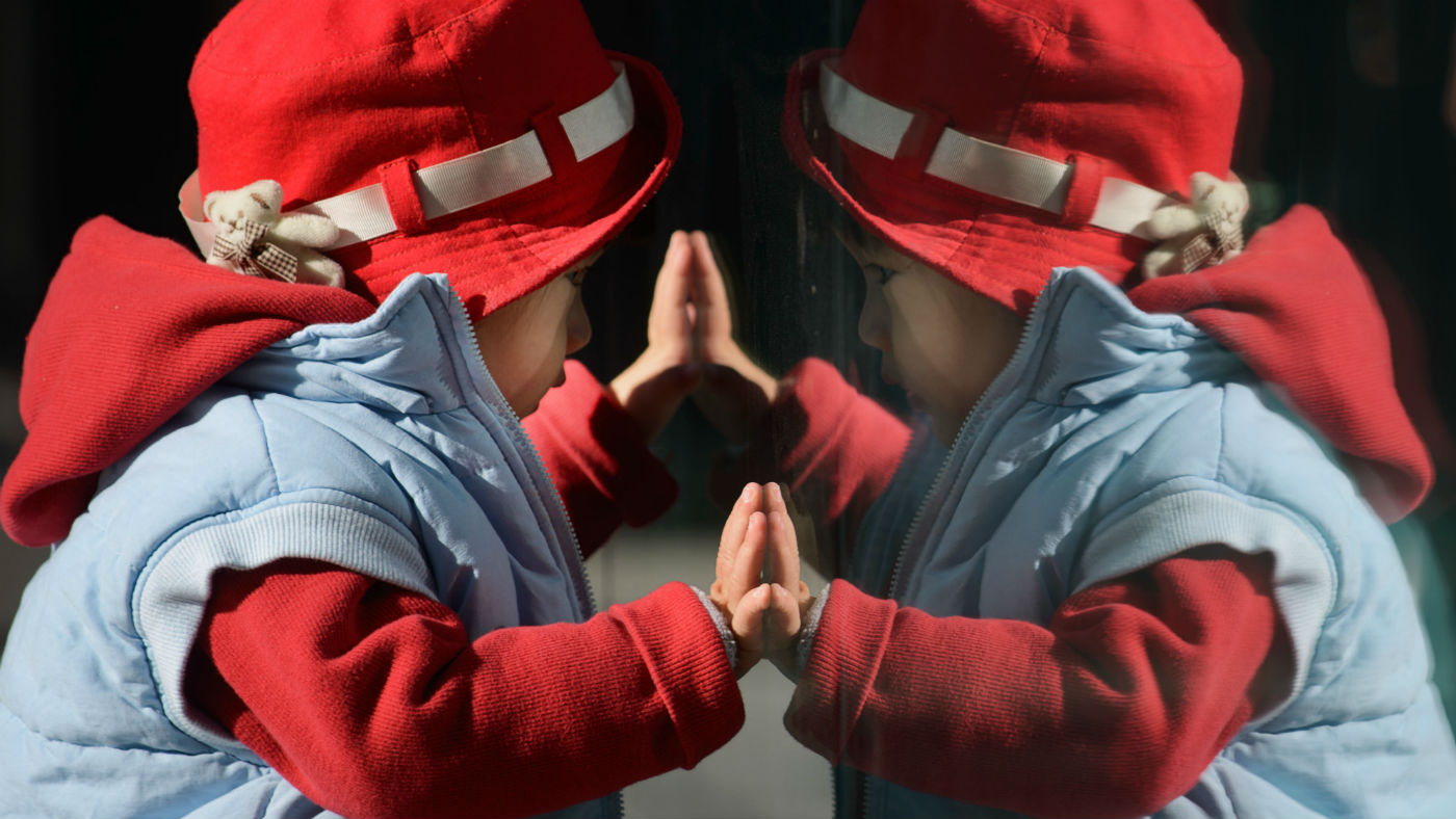 A child looks at his reflection in a window in Beijing