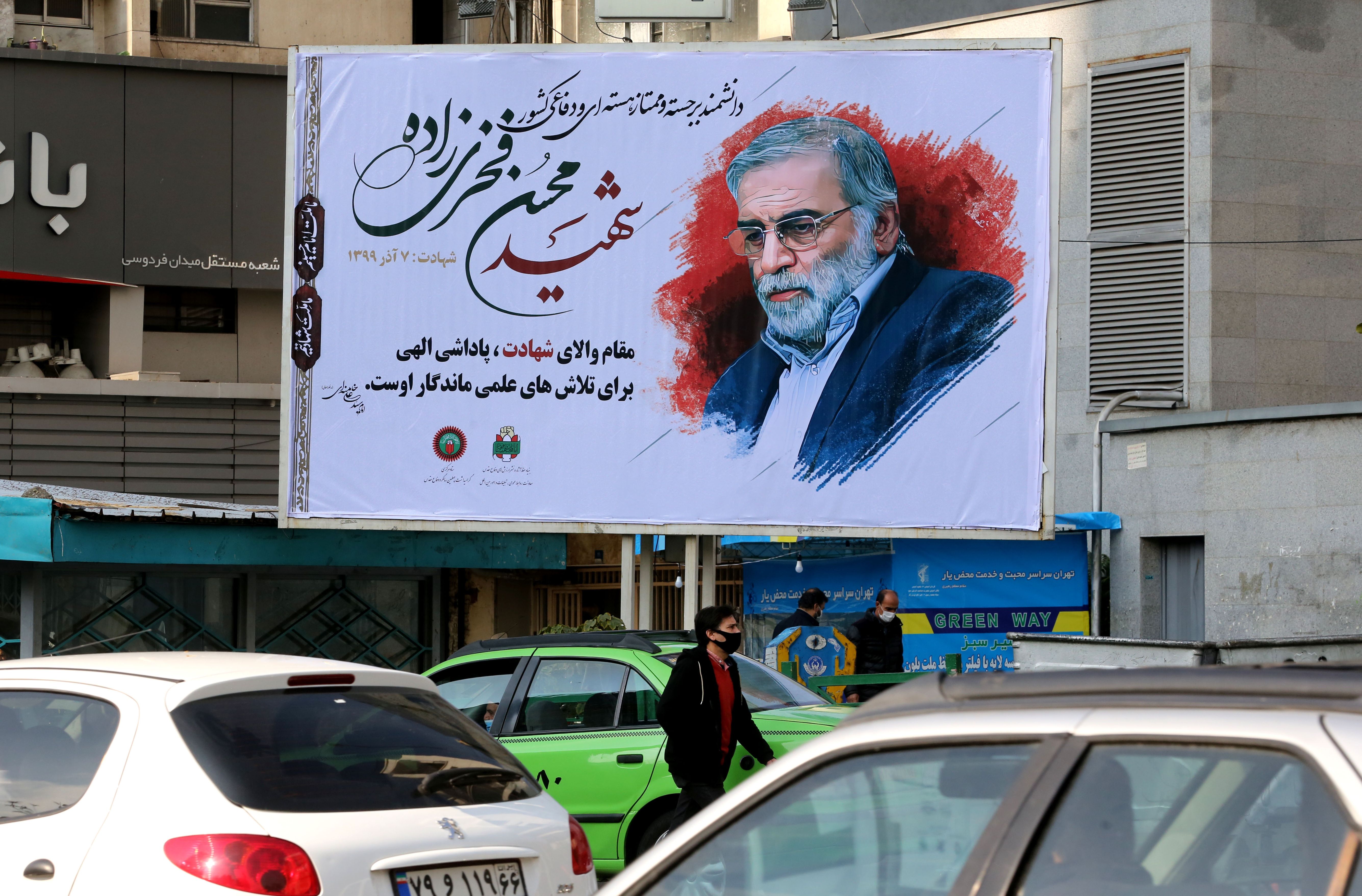 Vehicles drive by a billboard in honour of slain nuclear scientist Mohsen Fakhrizadeh in the Iranian capital Tehran, on November 30, 2020. - Iran laid to rest a nuclear scientist in a funeral