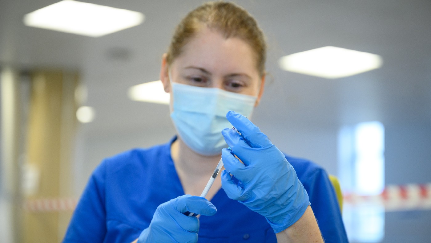 A woman in scrubs with a syringe 