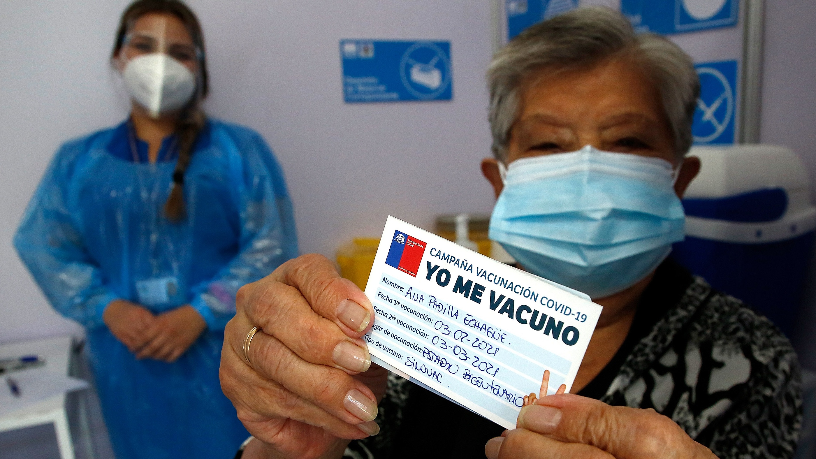 A Chilean woman shows her vaccination card