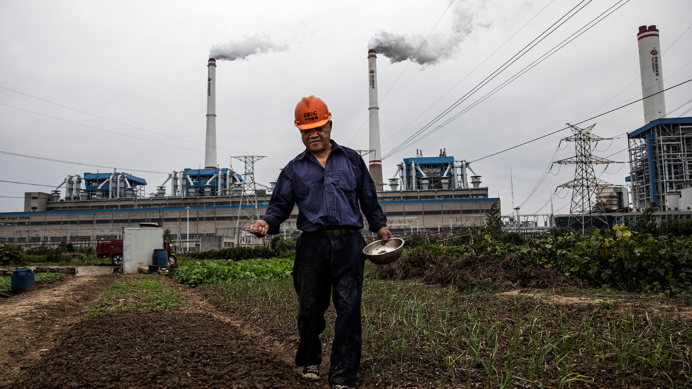 Man sows seeds outside coal power station in China