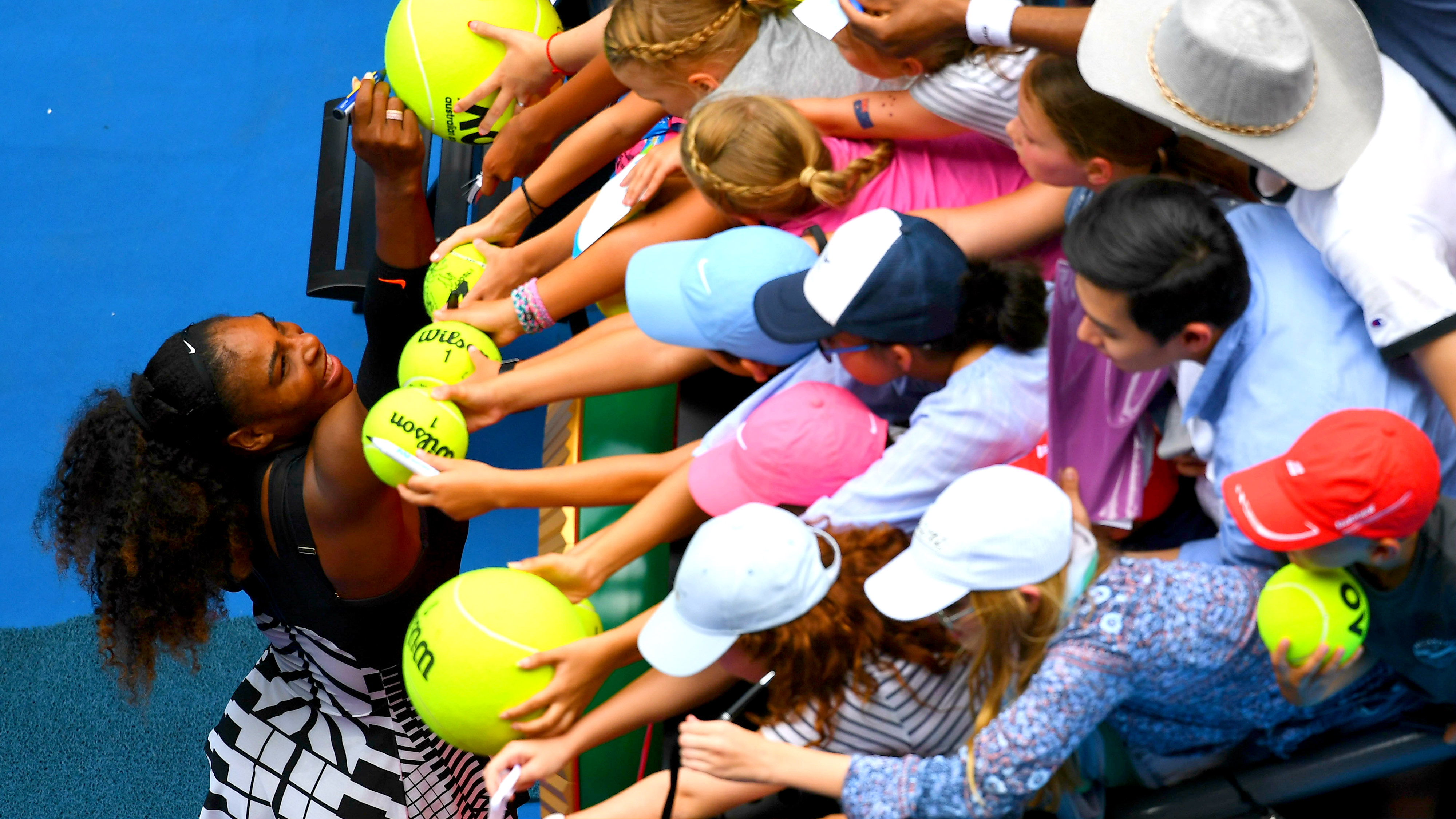 Serena Williams signs autographs for fans after winning her first-round match at the Australian Open in Melbourne