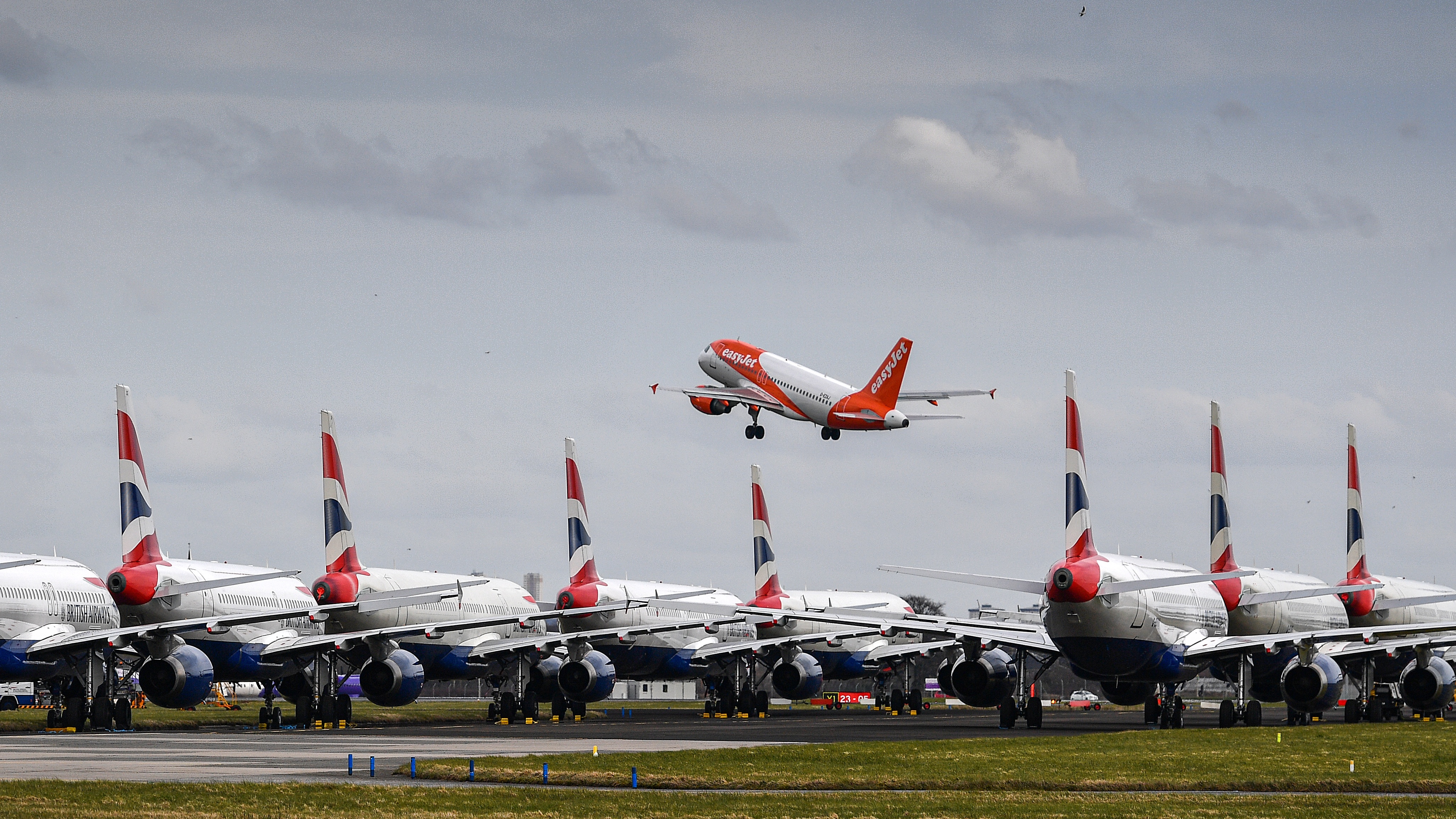 A fleet of British Airway planes sit on the runway at Glasgow Airport as an EasyJet plane takes off.