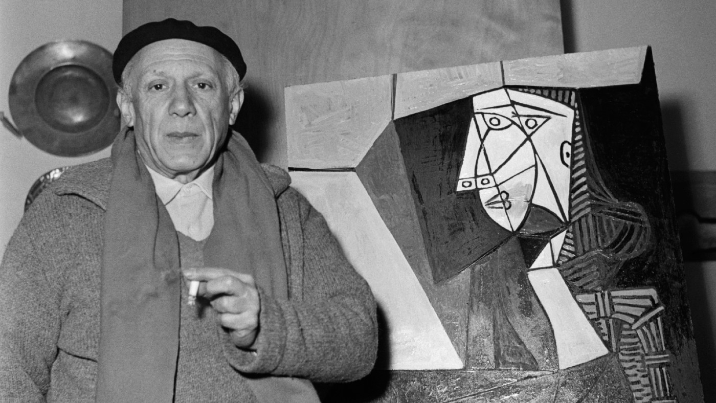 Pablo Picasso in front of one of his artworks
