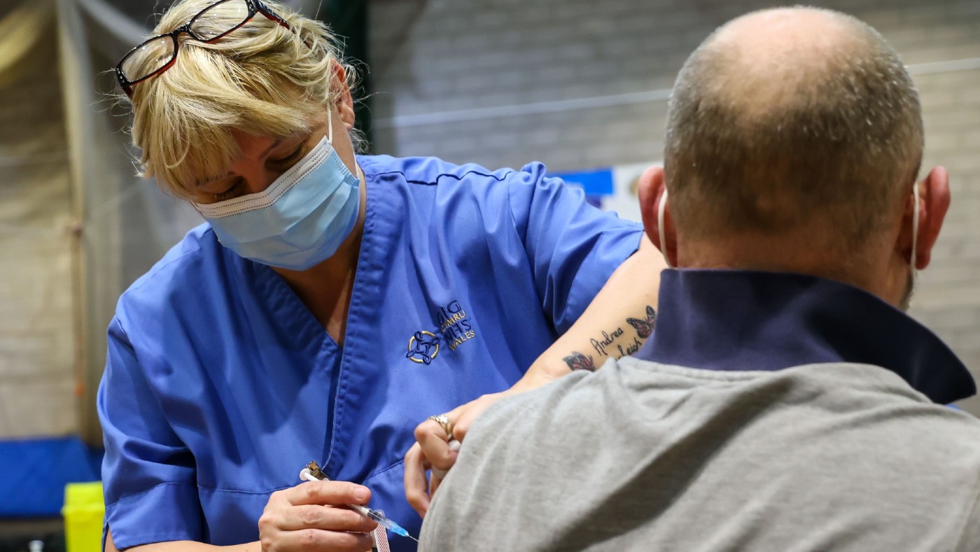 Man receiving vaccine from woman in scrubs