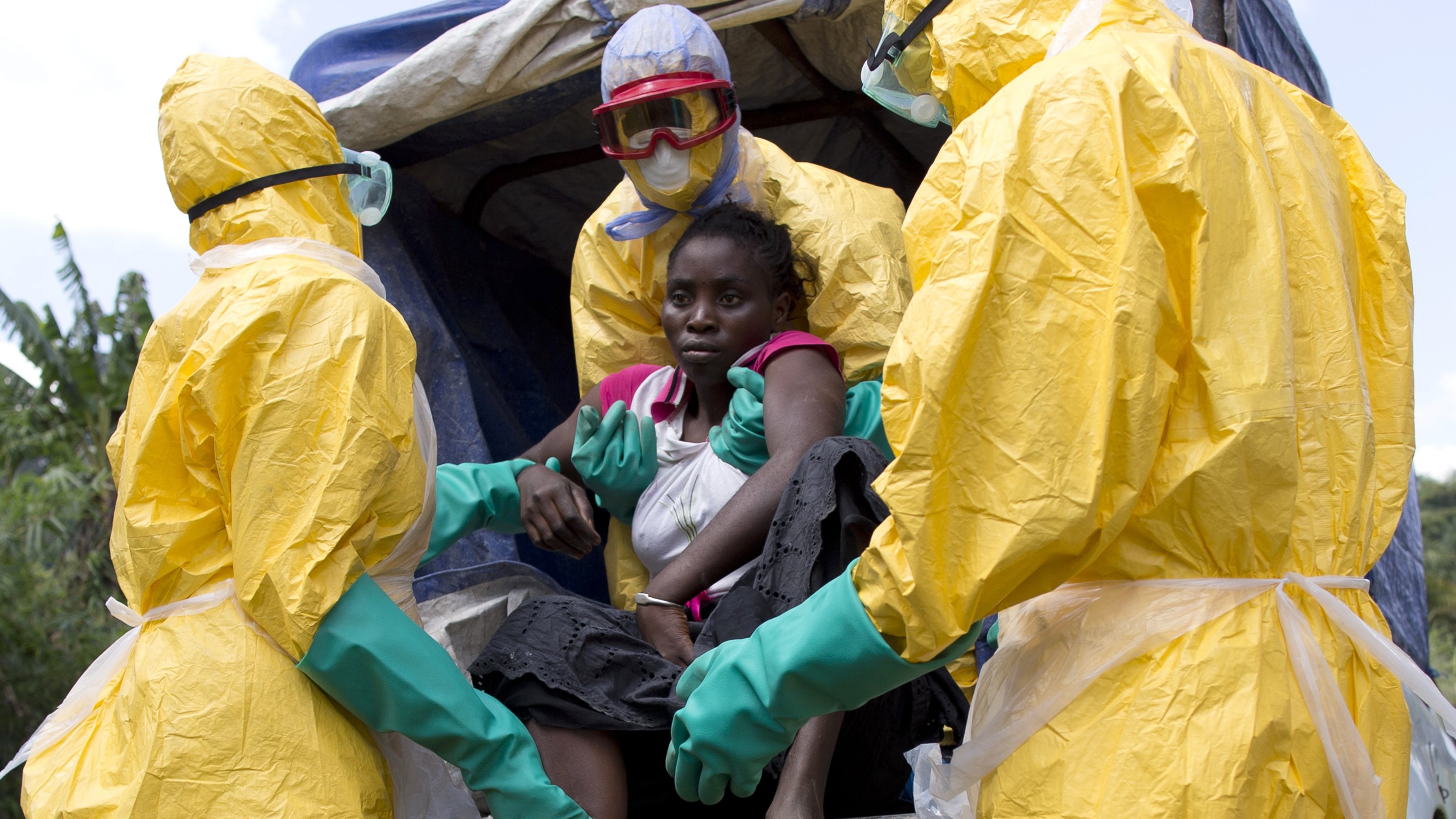 A woman suspected of suffering from Ebola is helped into a van by aid workers.