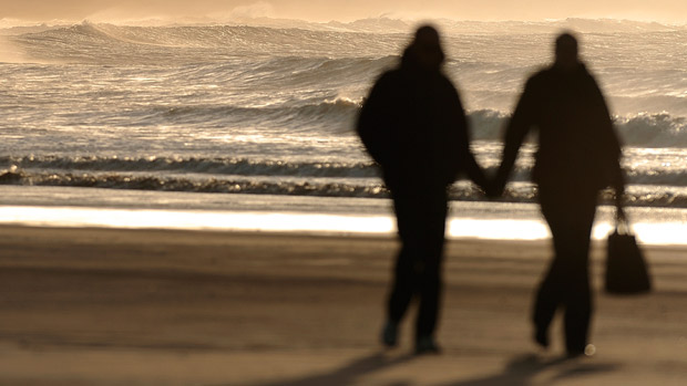 Couple walking on beach in silhouette