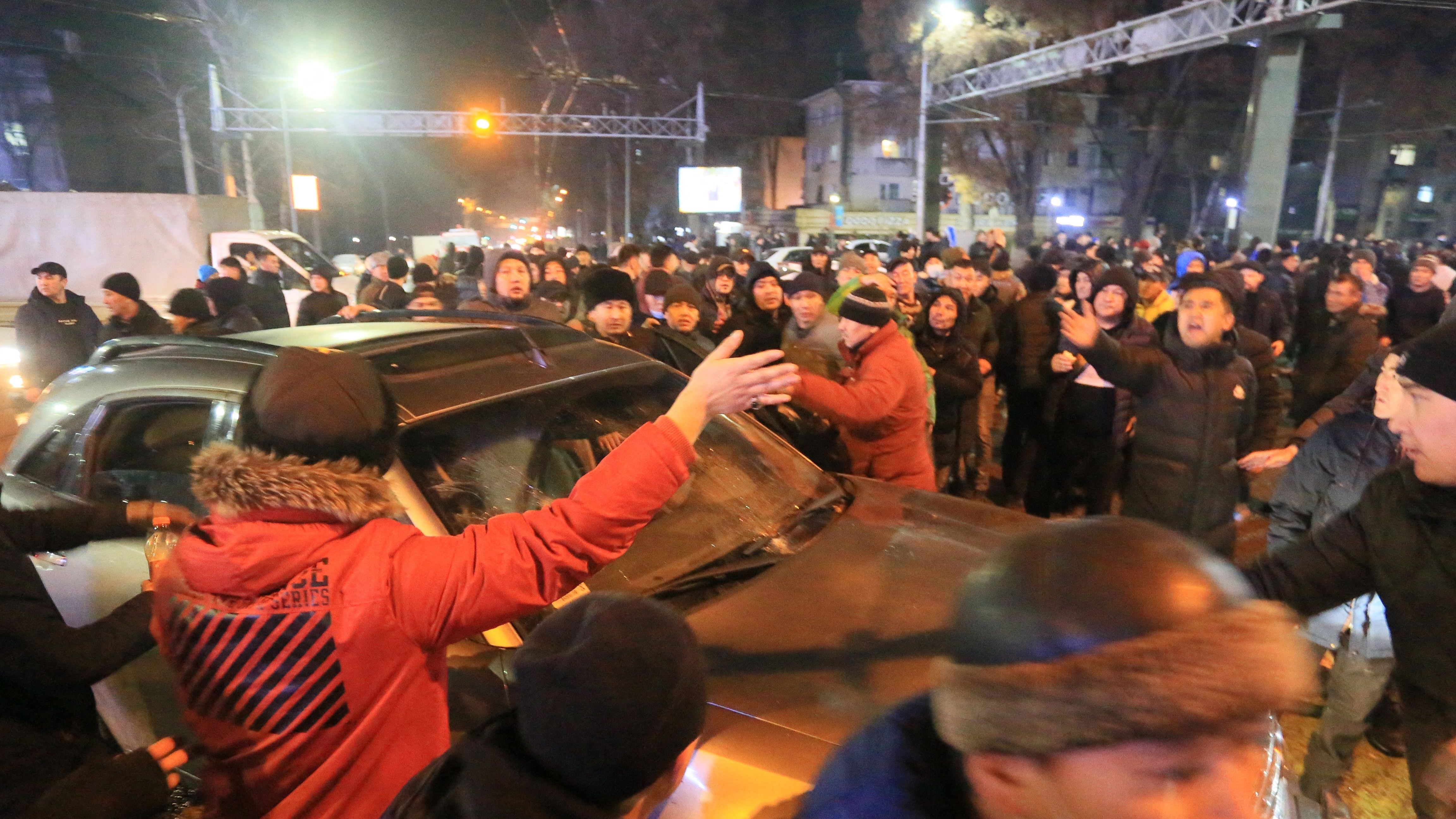 Protestors circle a car in Almaty, Kazakhstan