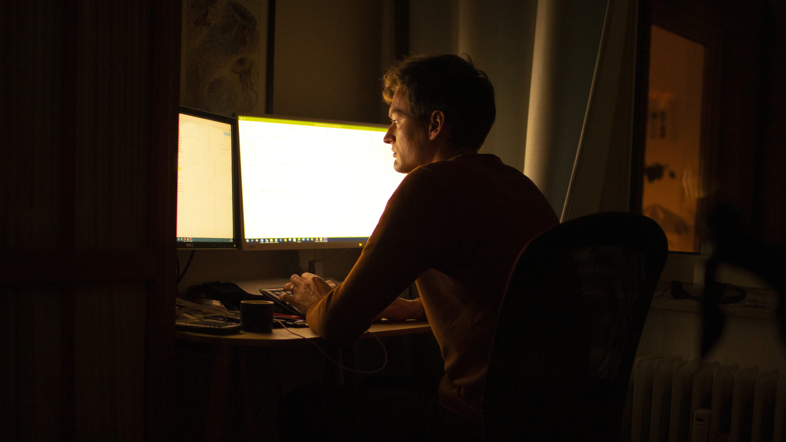 A man using a computer in a dark room