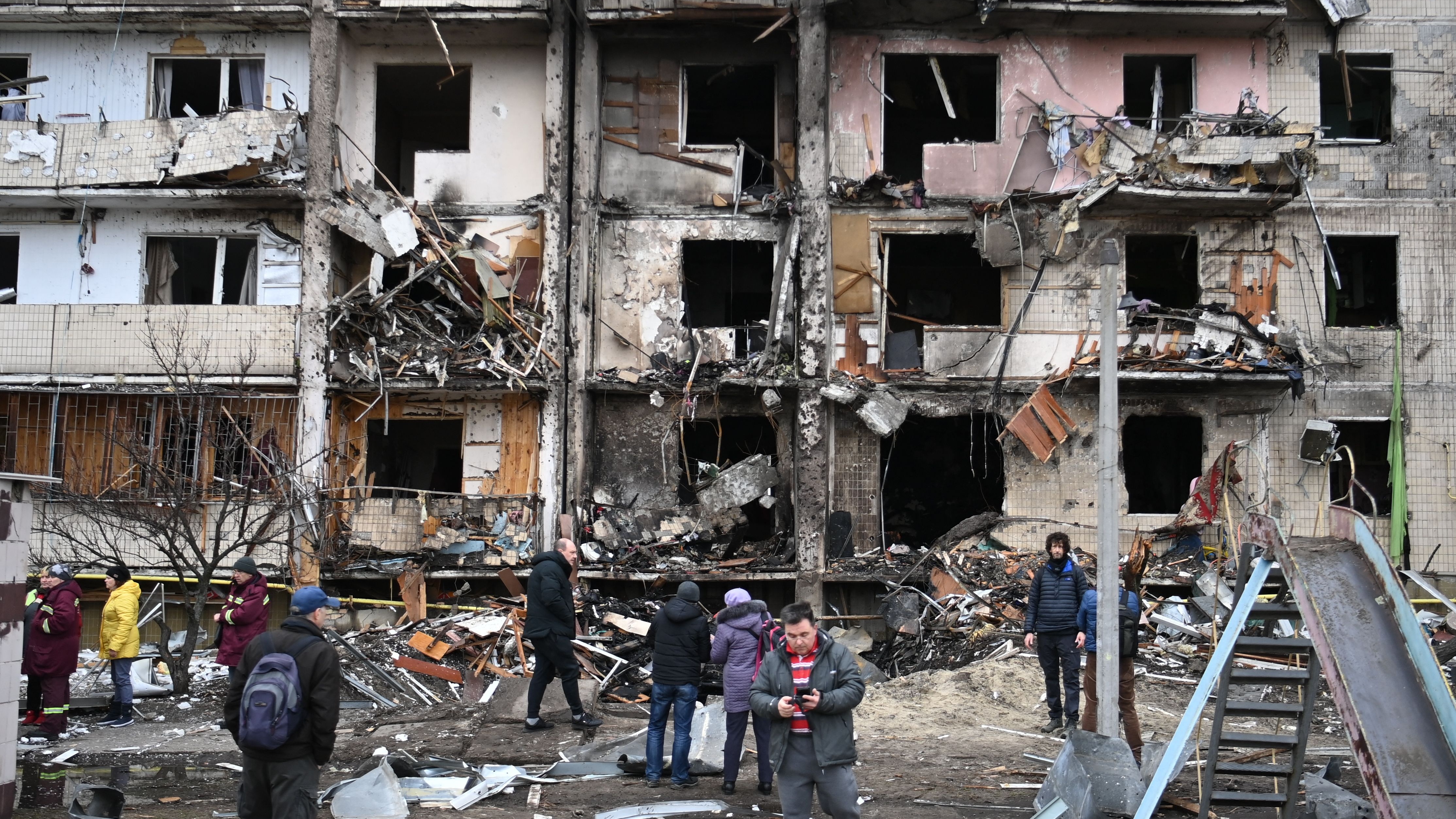 25 February: People gather outside an apartment block in a Kyiv suburb hit by a Russian shell  