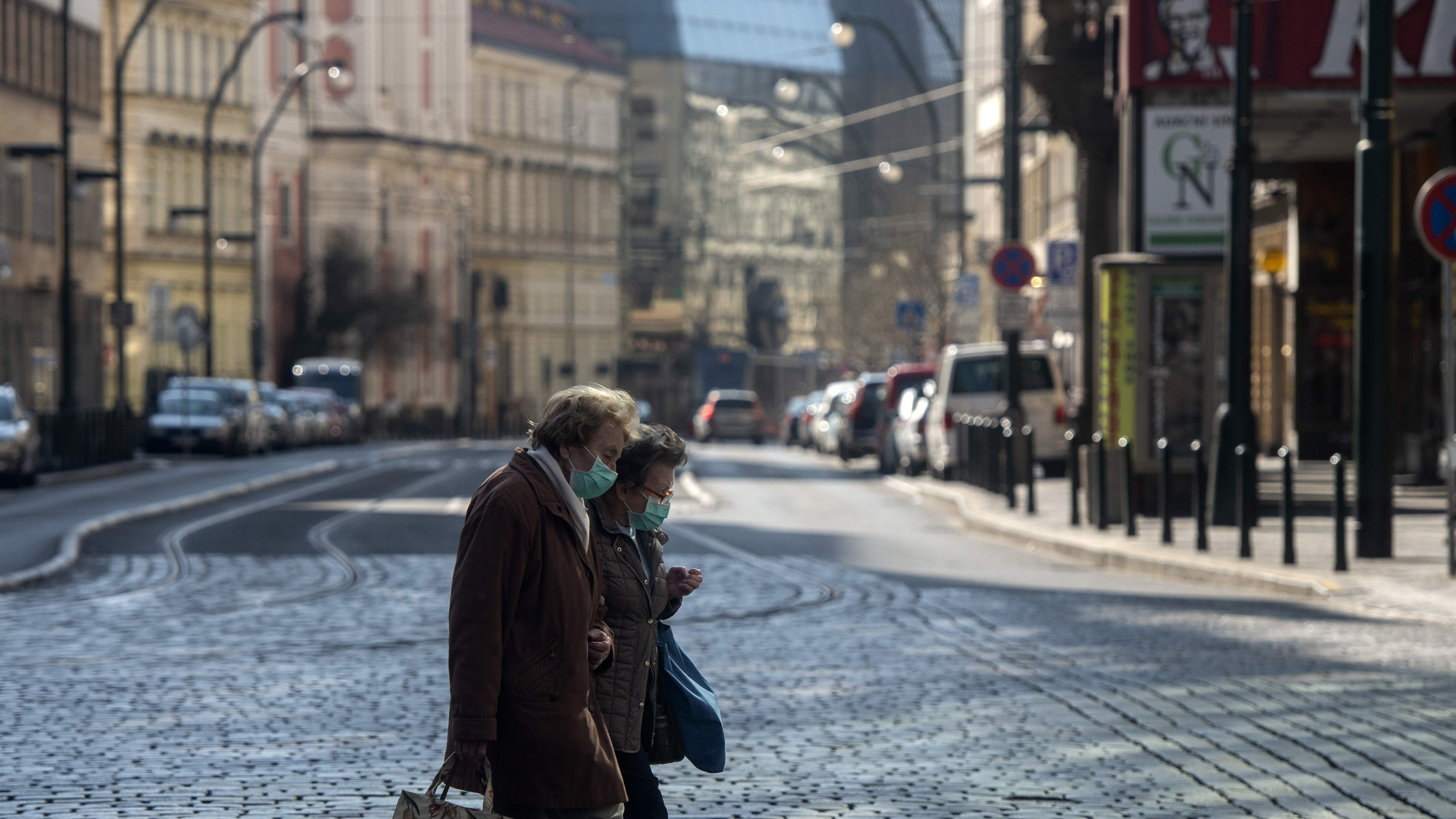 Two ladies cross the road in Prague, Czech Republic wearing face masks