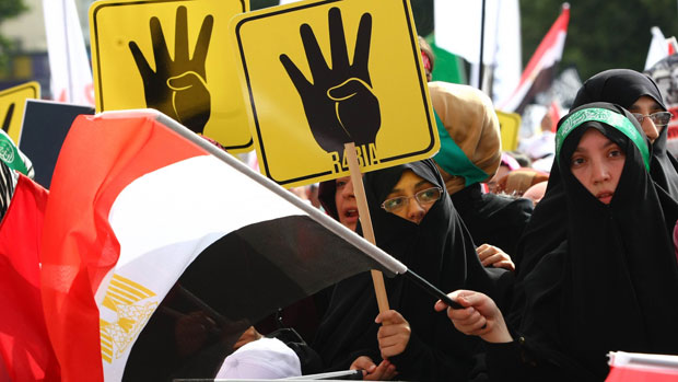 Protesters hold placards showing the &#039;Rabia sign&#039; which has become the symbol of the Rabaa massacre