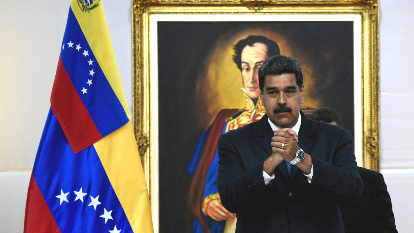 Nicolas Maduro stands in front of a portrait of Simon Bolivar in the presidential palace