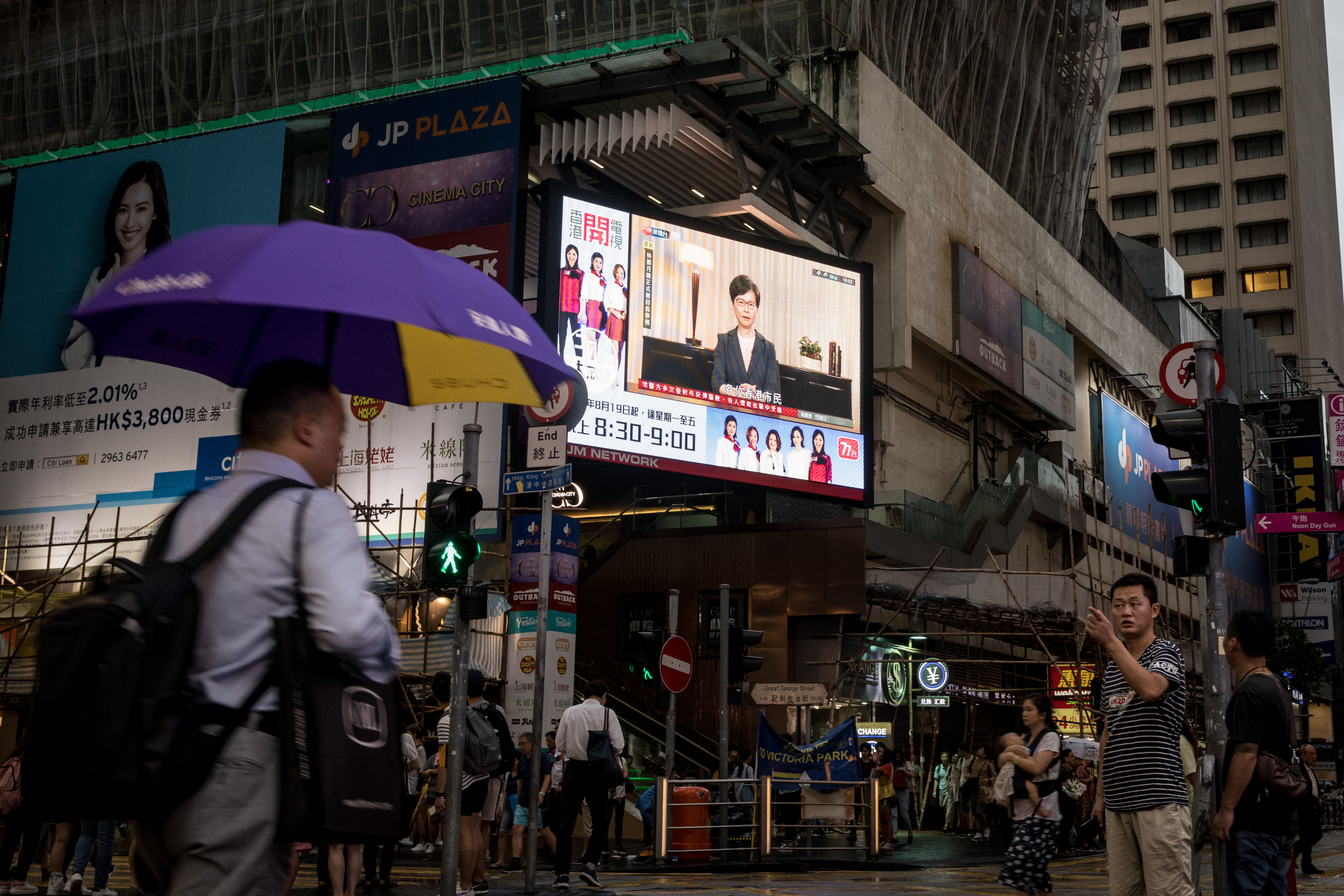 HONG KONG, CHINA - SEPTEMBER 04: People walk past a big screen replaying Hong Kong Chief Executive Carrie Lamannouncing the formal withdrawal of the extradition bill on September 04, 2019 in 