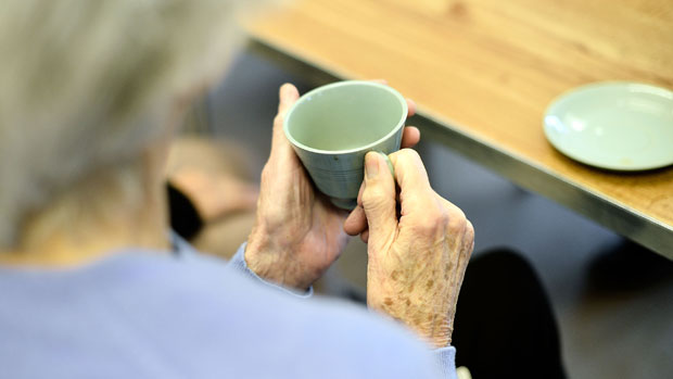An elderly lady enjoys a cup of tea at an AgeUK Centre