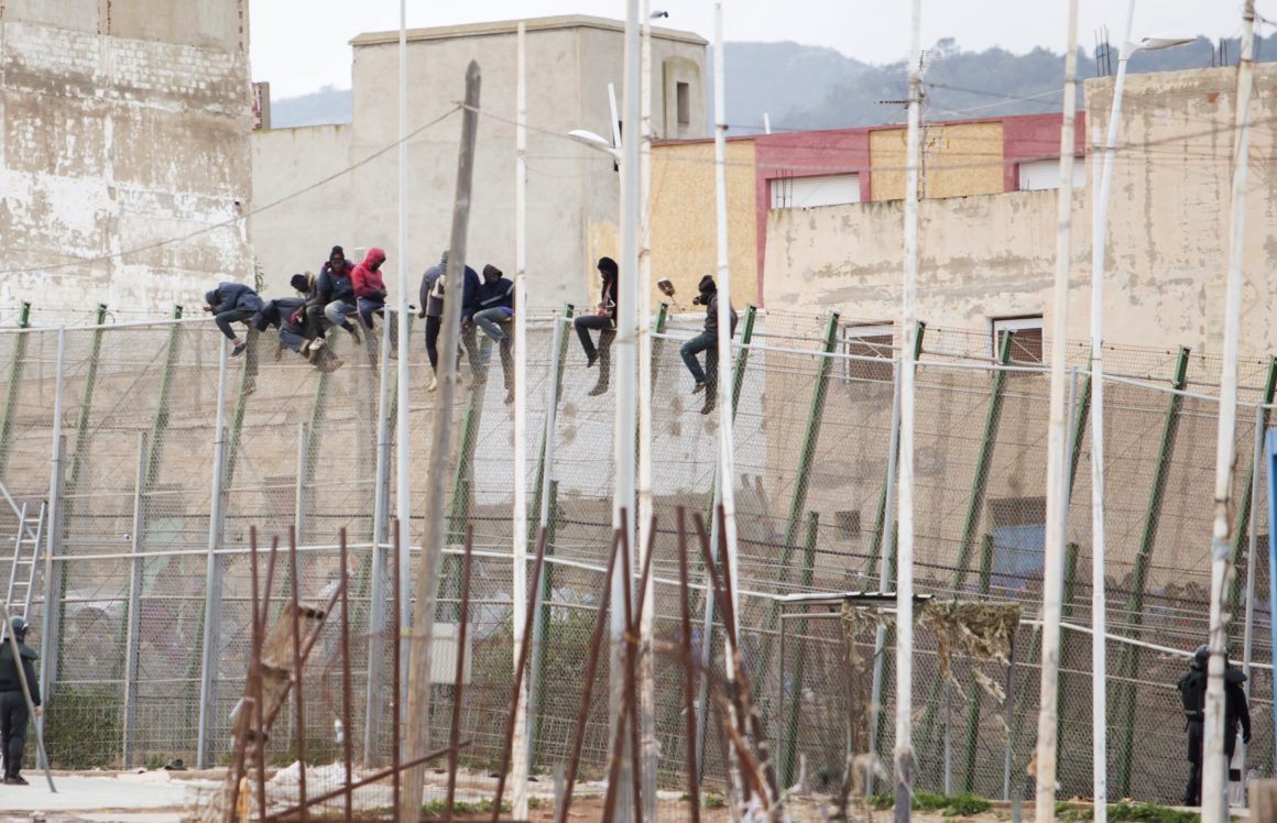 Would-be immigrants sit atop a border fence after attempting to cross from Morocco to the Spanish enclave of Melilla on February 10, 2015. More than 600 immigrants tried today to climb over t