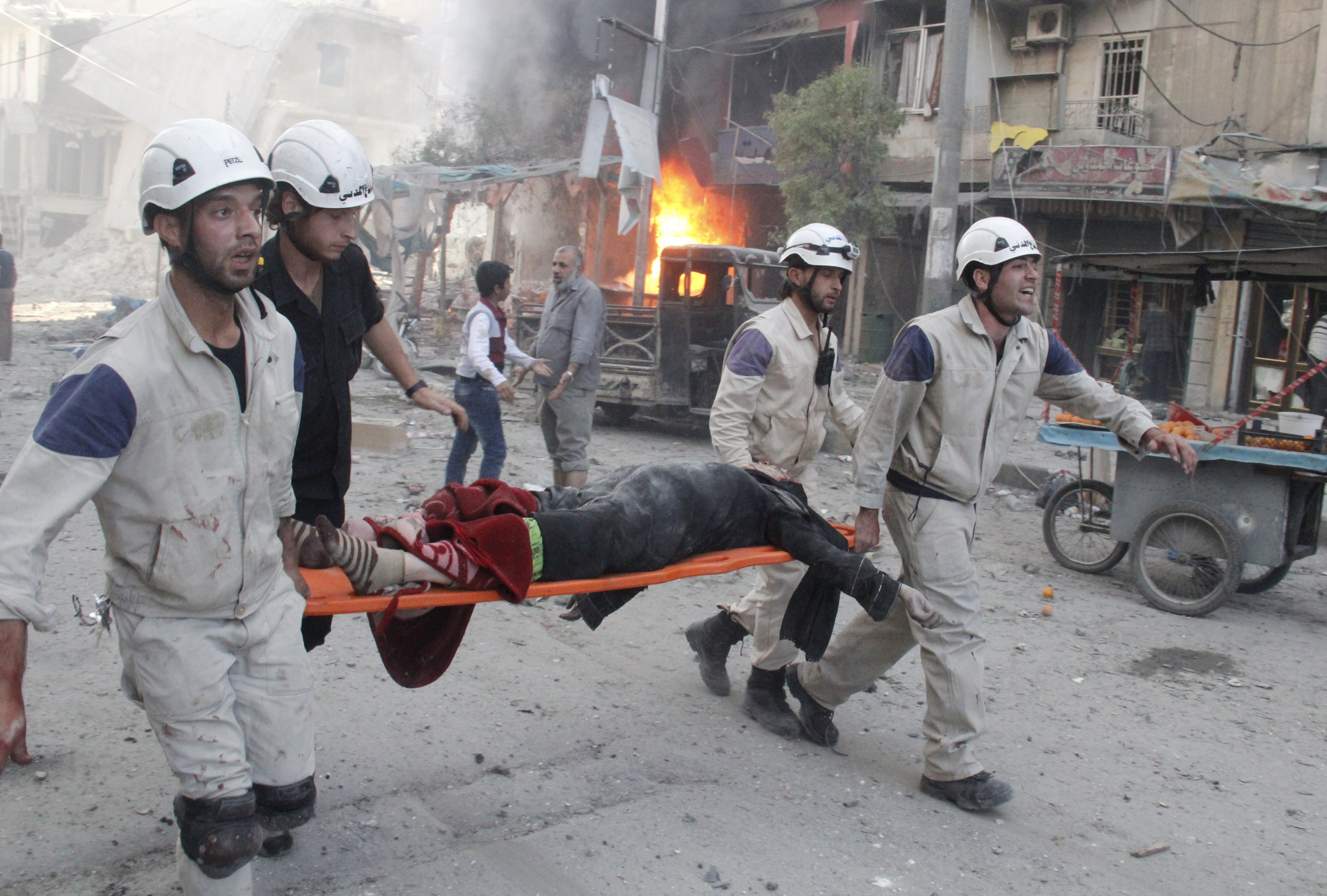 Syrian rescue workers carry the body of a woman in Aleppo