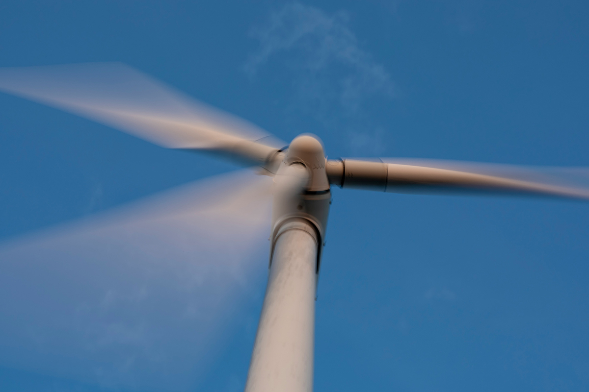 A spinning wind turbine seen from below