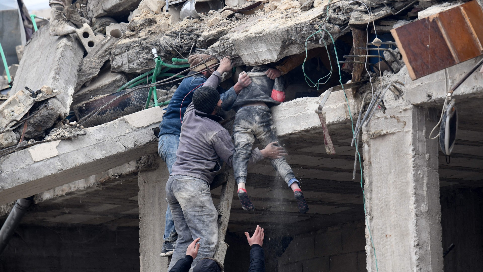 An injured girl is brought out of the rubble of a building in Jandaris, Syria