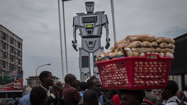 A man walks by with a basket of bread during the official presentation ceremony of three new human-like robots 