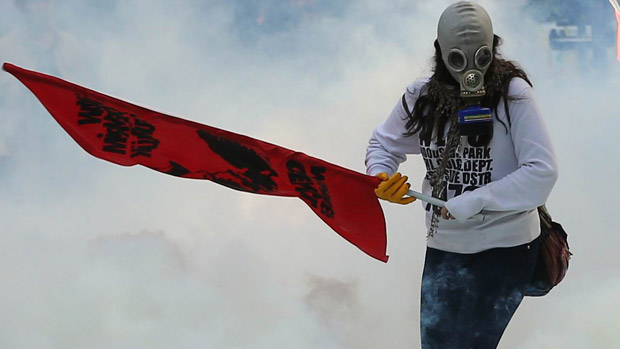 A person holds a flag as Turkish police uses tear gas and water cannon