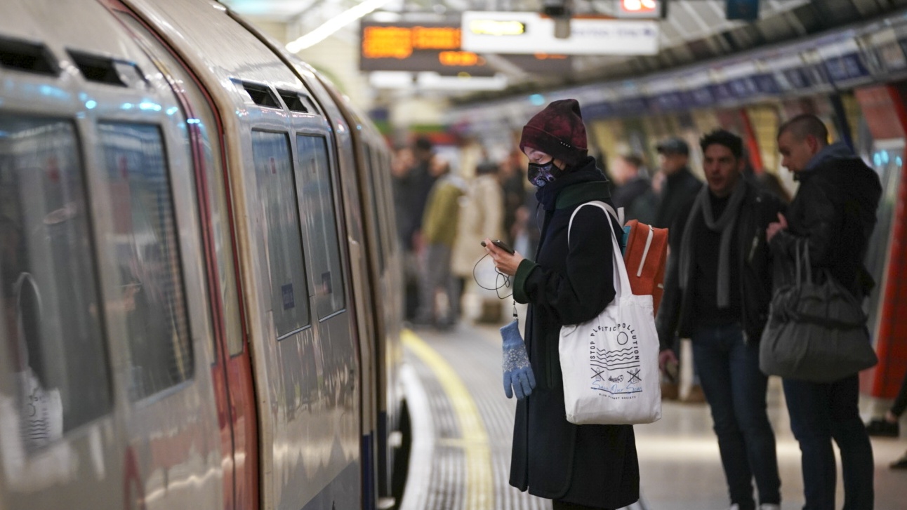 A woman wearing a face mask waits on the platform for the London Underground