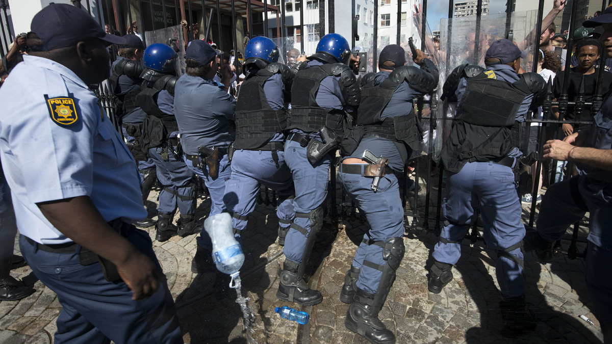 Members of the South African Police Services force a gate closed against students from the University of Cape Town, protesting against fee hikes, after they forced their way into the South Af