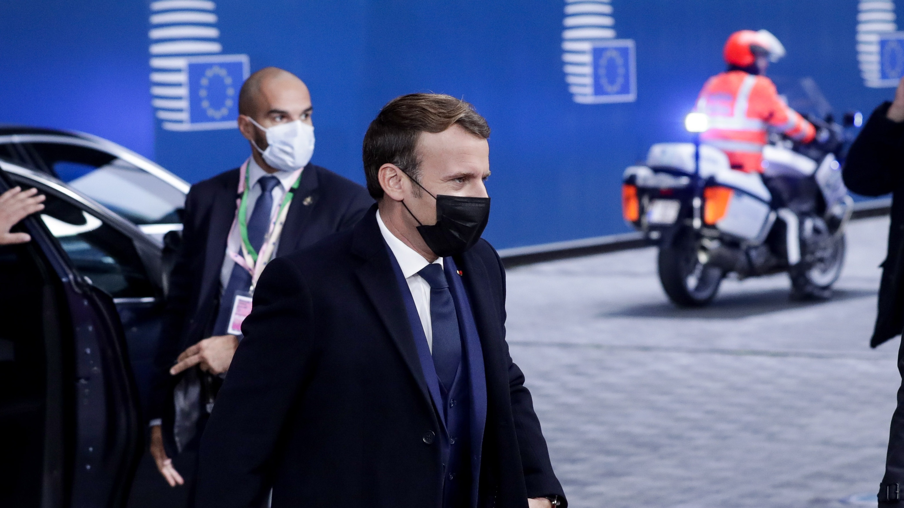 Emmanuel Macron arrives at the European Parliament building wearing a black face mask.