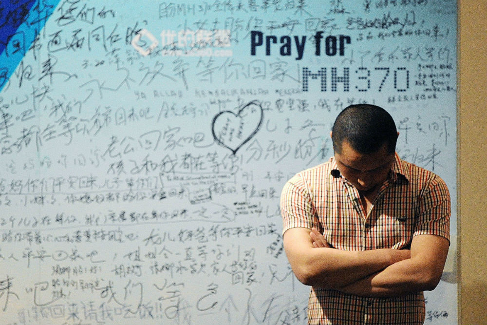 A victim&#039;s relative stands in front of tributes to flight MH370