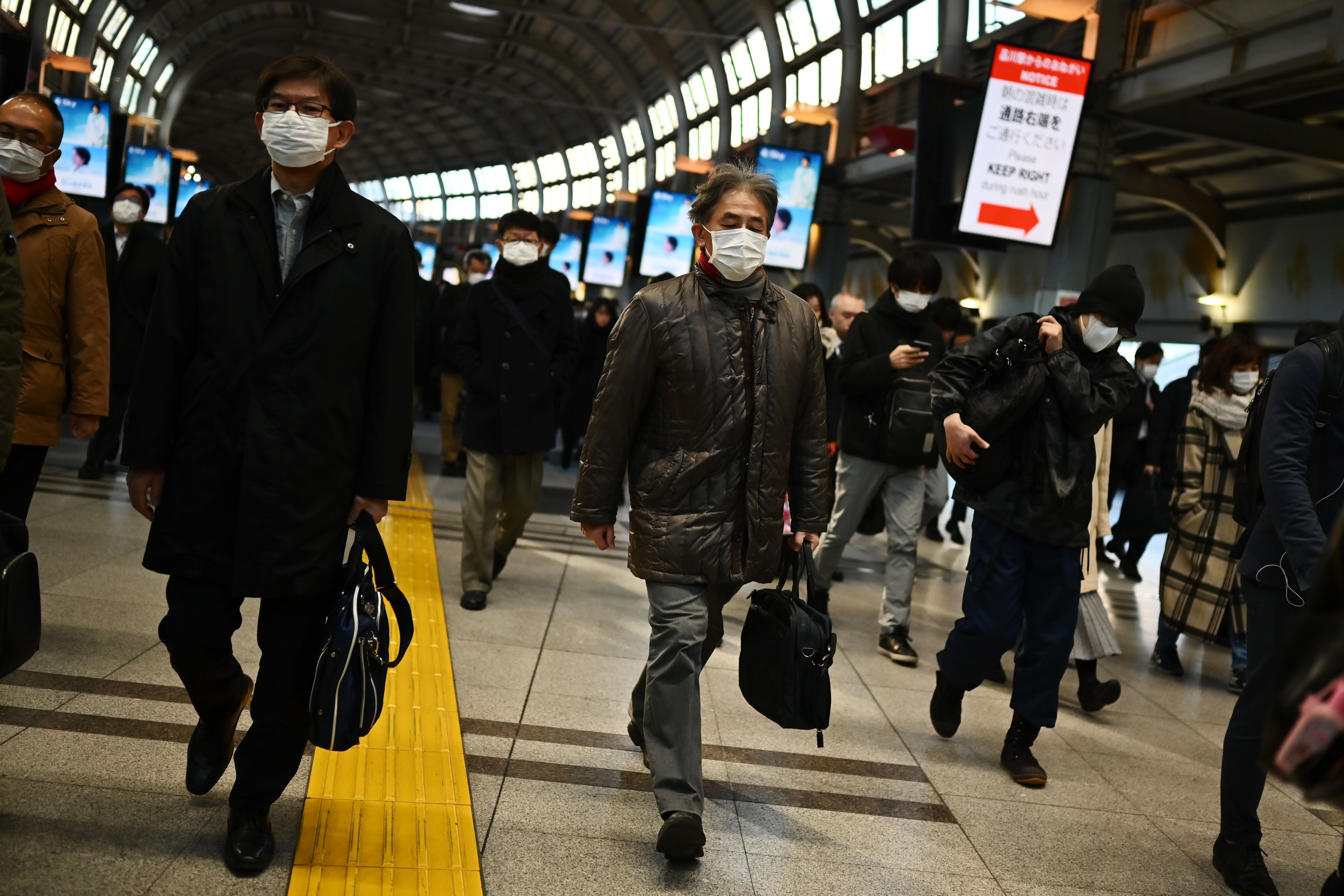 Mask-clad commuters make their way to work during morning rush hour at the Shinagawa train station in Tokyo on February 28, 2020. - Tokyo&#039;s key Nikkei index plunged nearly three percent at th