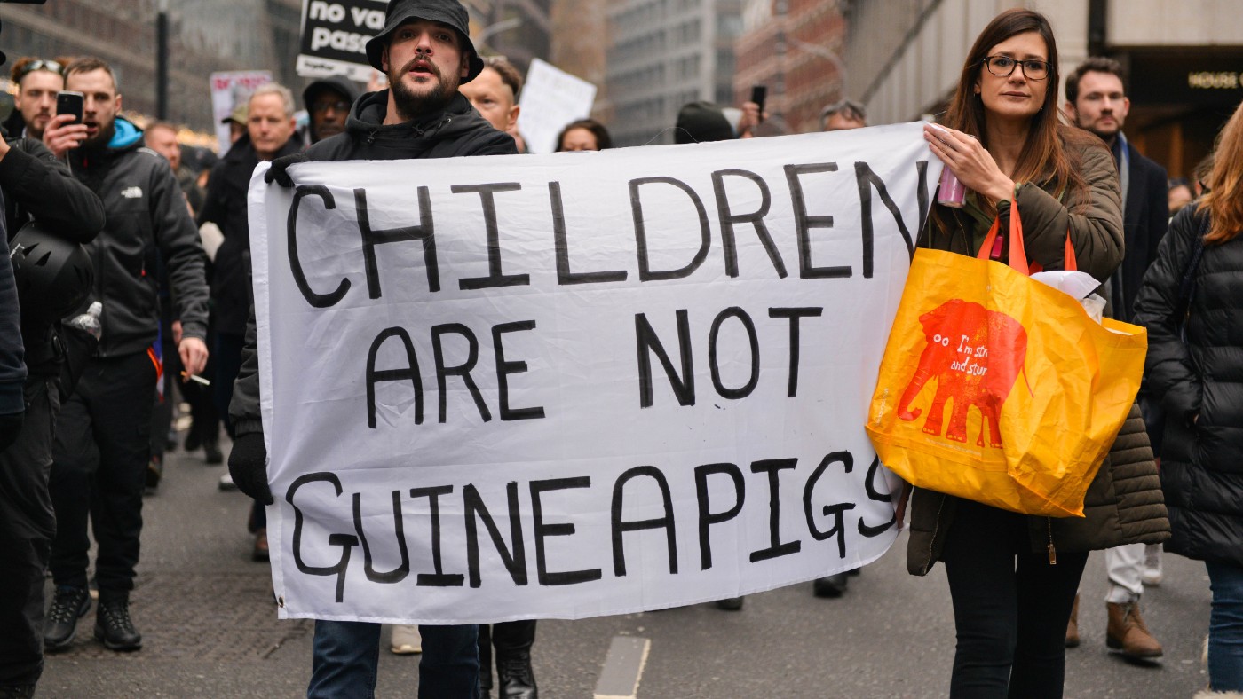 Protester with 'Children are not guinea pigs' sign