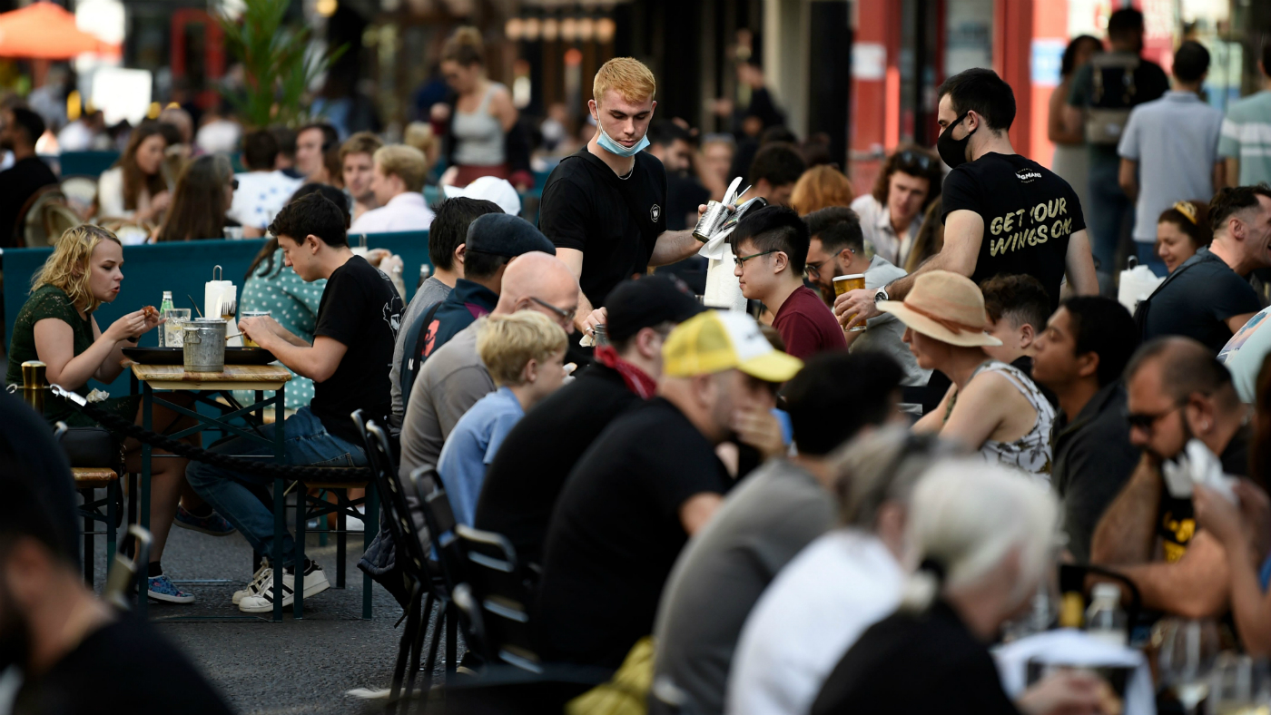 People sit outside at restaurants in Soho, London.