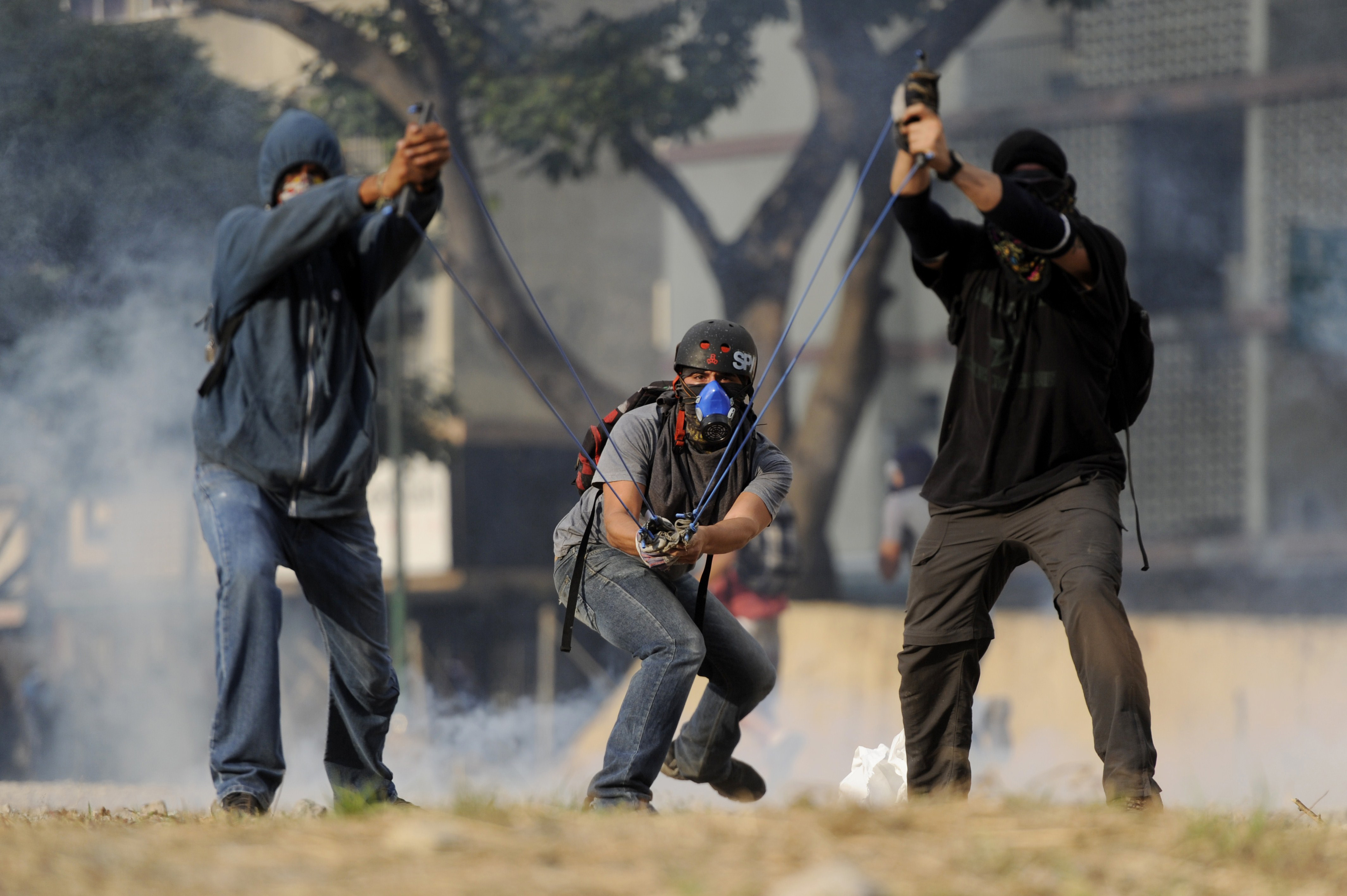 Opposition activists throw stones with a slingshot during a protest against the government of Venezuelan President Nicolas Maduro, in Caracas on March 10, 2014. Two rival protests today were 