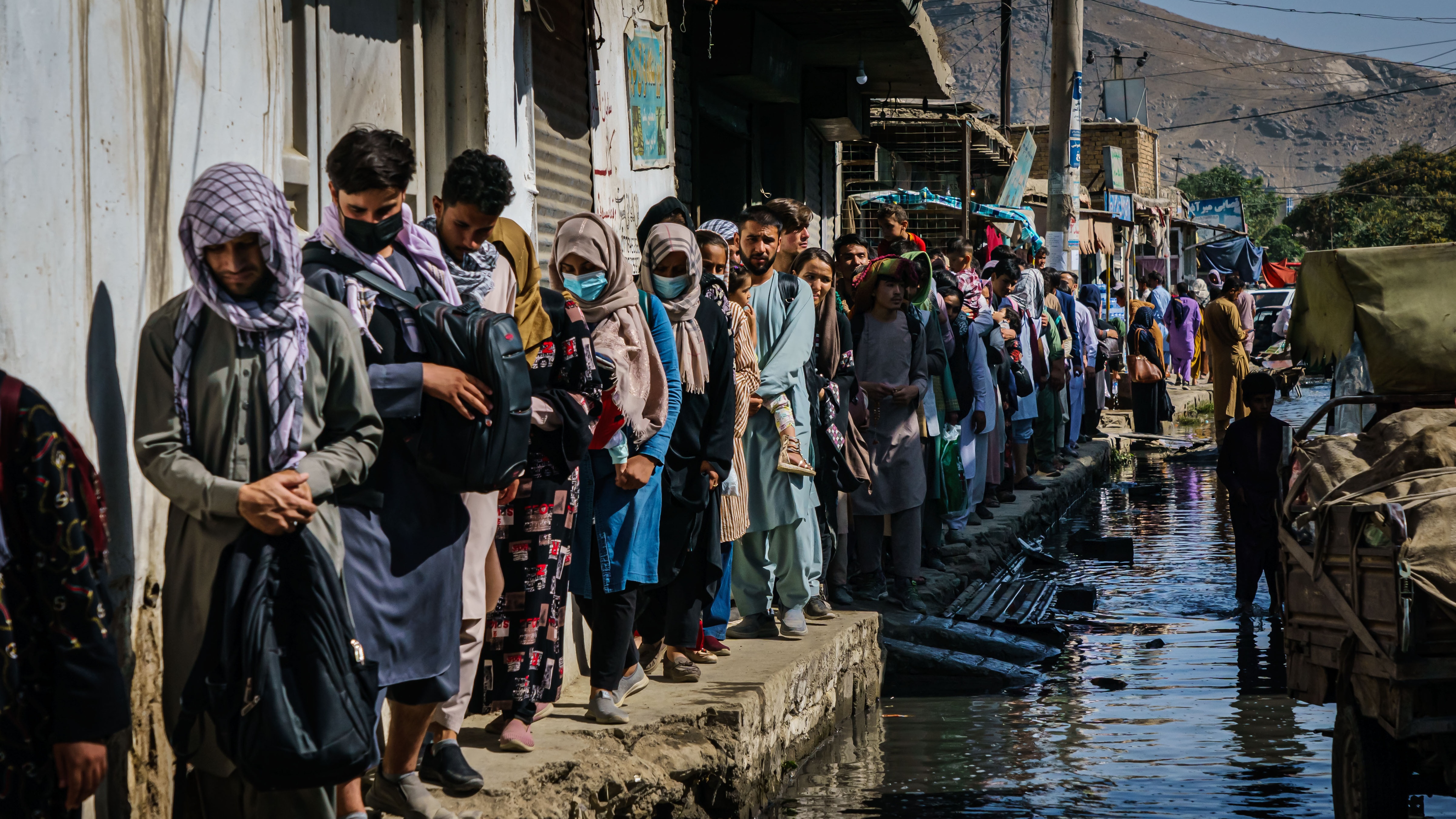 Afghans make their way through a flooded street towards Kabul airport