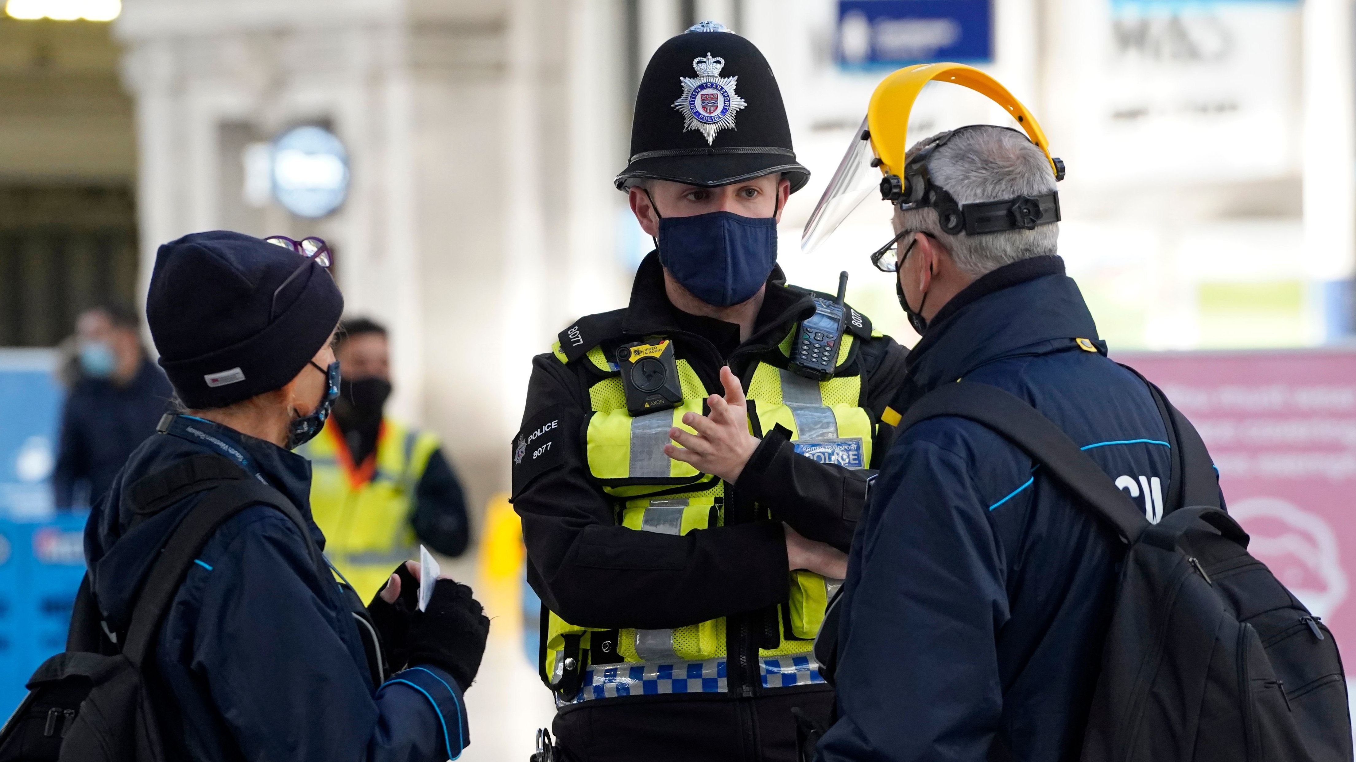 A member of the British Transport Police speaks with travellers at Waterloo Station