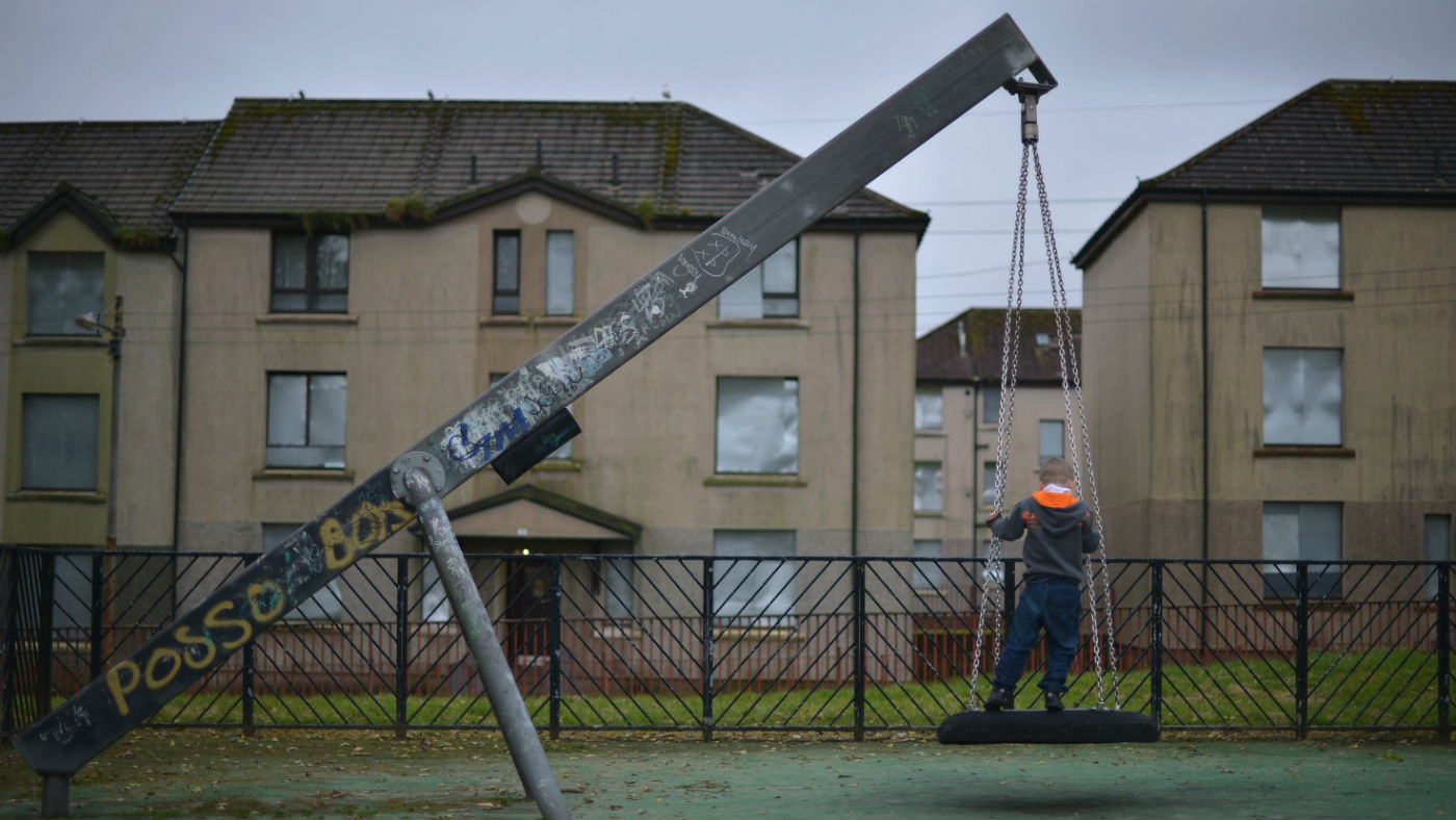 A young boy plays in a park near disused housing in Glasgow, Scotland
