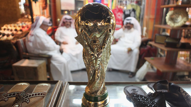 Men sit at a market stall in Qatar with a replica of a trophy