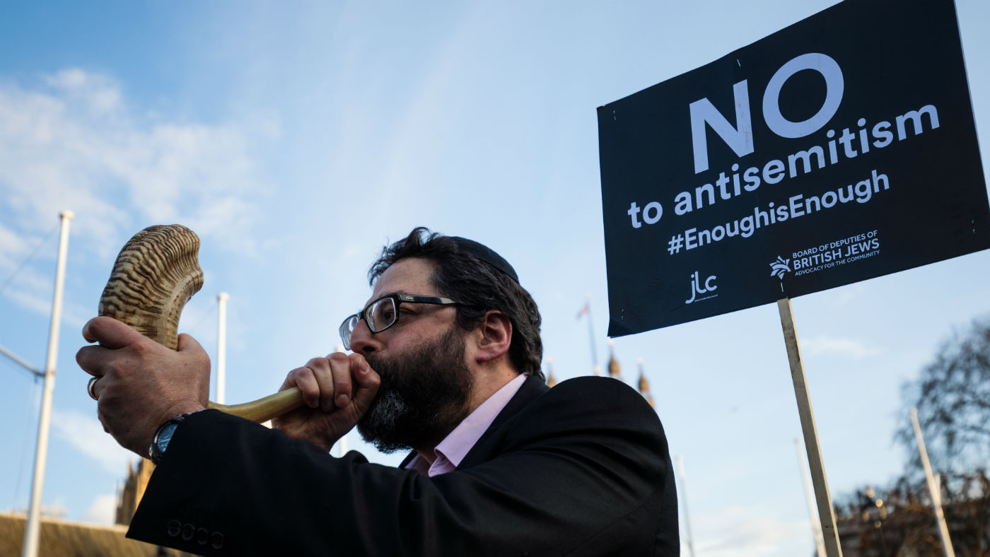 A protester blows through a shofar during a demonstration in Parliament Square against anti-Semitism in the Labour Party 
