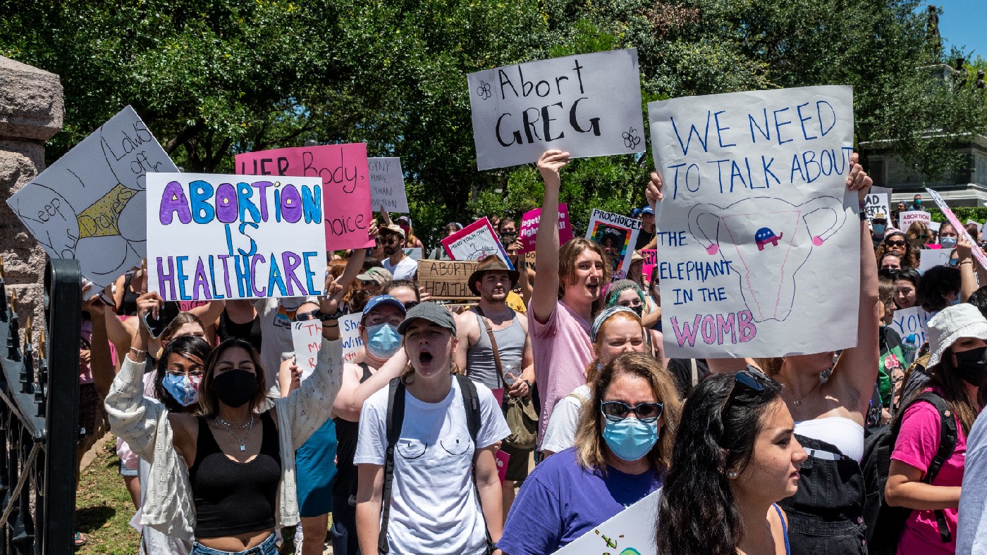 Protesters hold up signs at a protest outside the Texas state capitol on 29 May 2021 