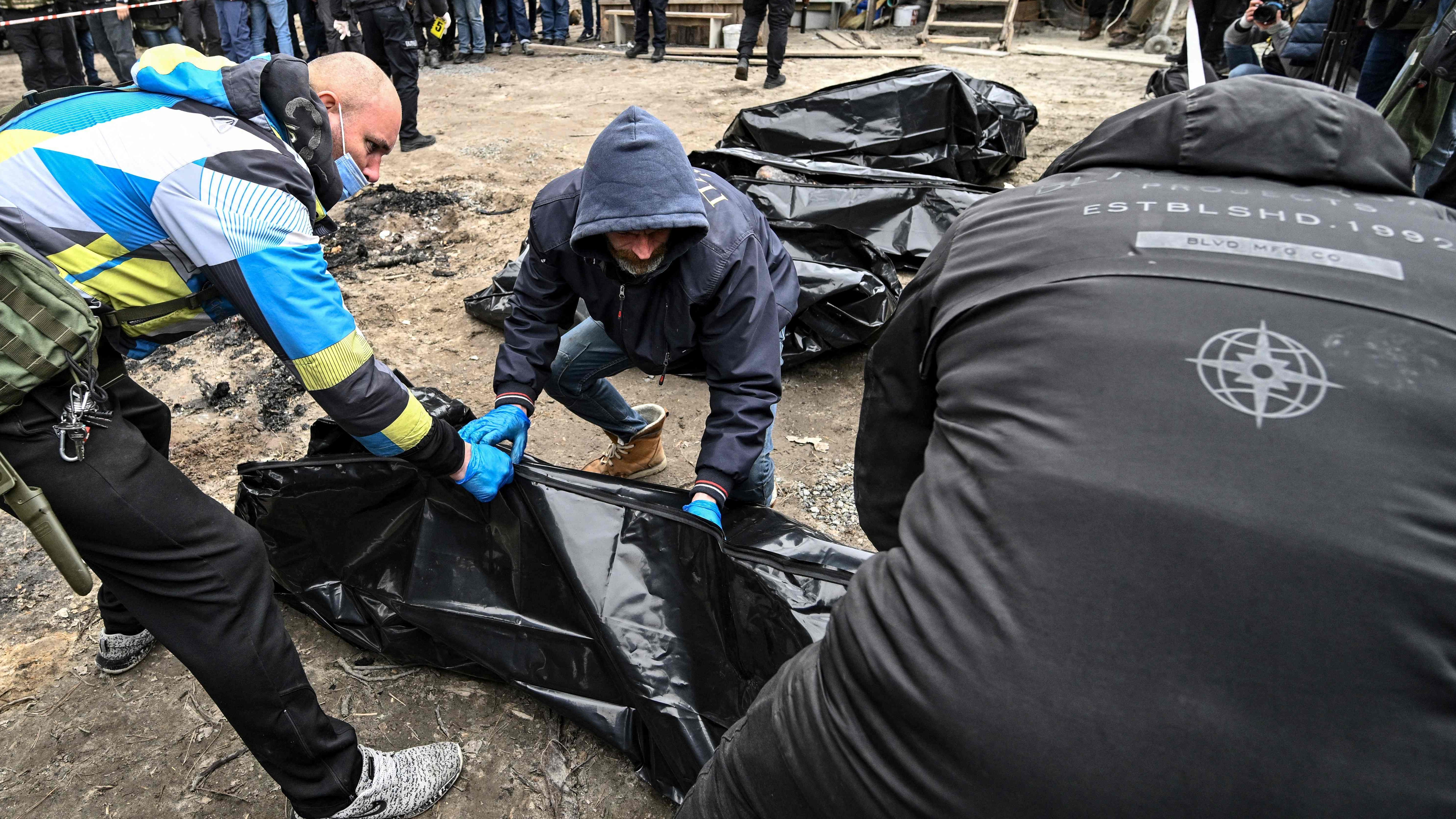 Volunteers put bodies into body bags in the city of Bucha