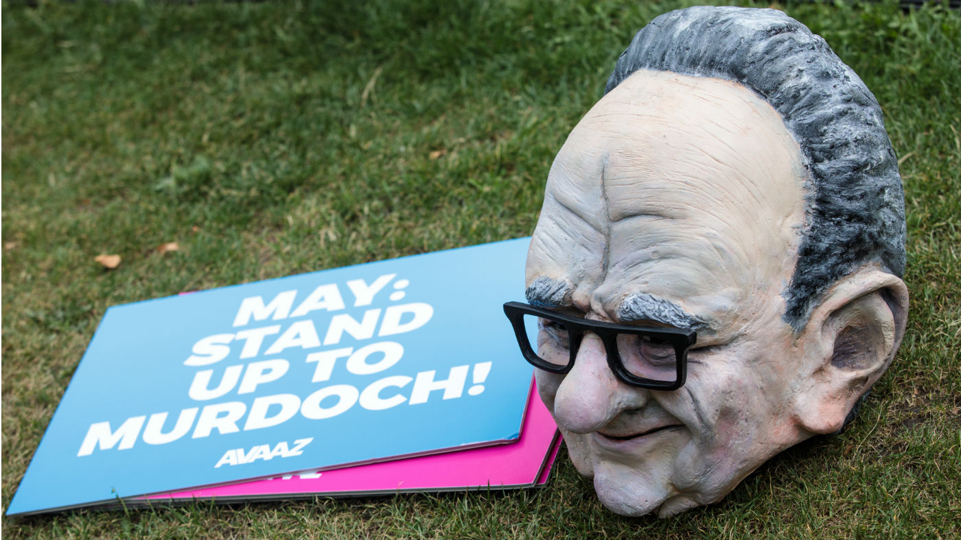 A puppet head of Rupert Murdoch sits next to an anti-takeover placard outside Parliament 