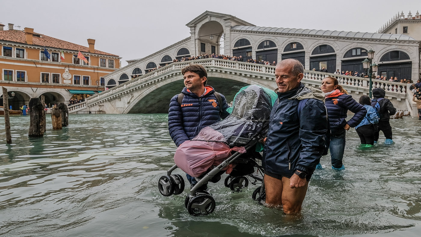 VENICE, ITALY - OCTOBER 29: Tourists carry a stroller through the flood waters on October 29, 2018 in Venice, Italy. Today due to the exceptional level of the &quot;acqua alta&quot; that reaced 156 cm 