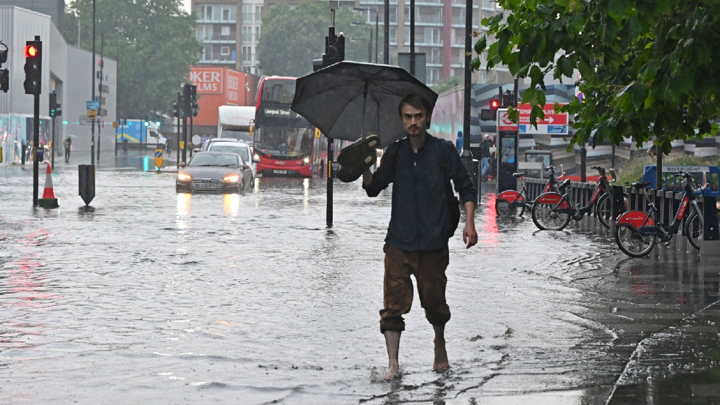 A pedestrian walks bare-footed along a flooded road 