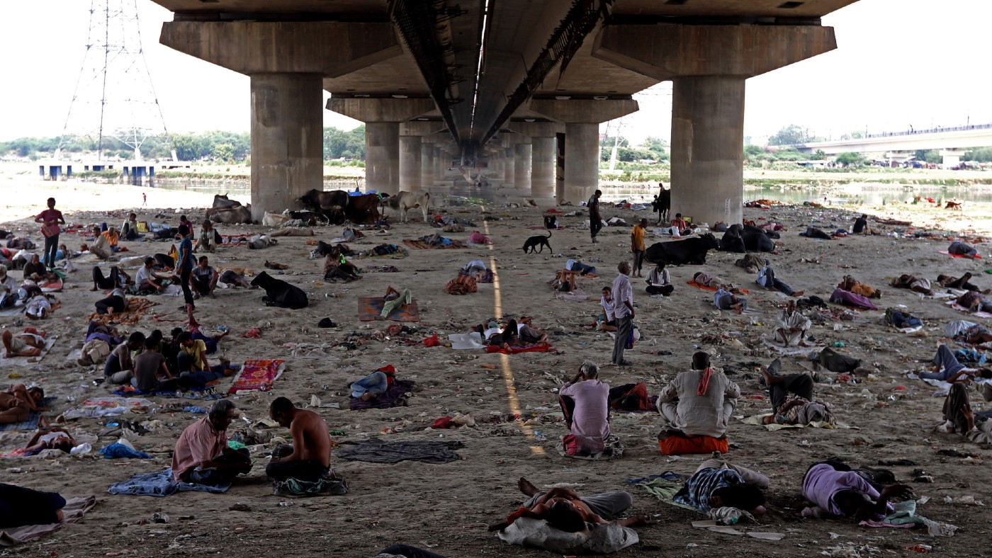 People rest in the shade under a bridge