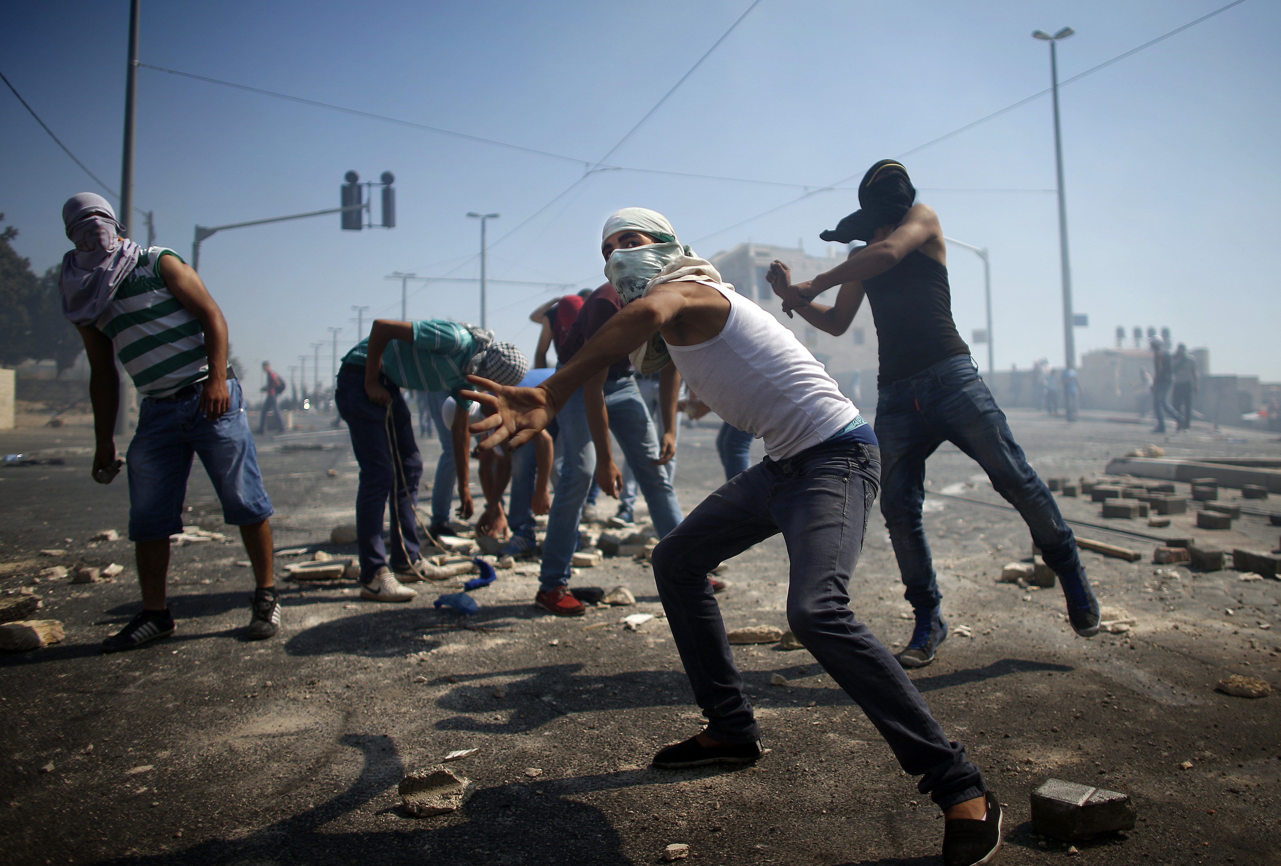 Palestinian protesters throw stones towards Israeli police