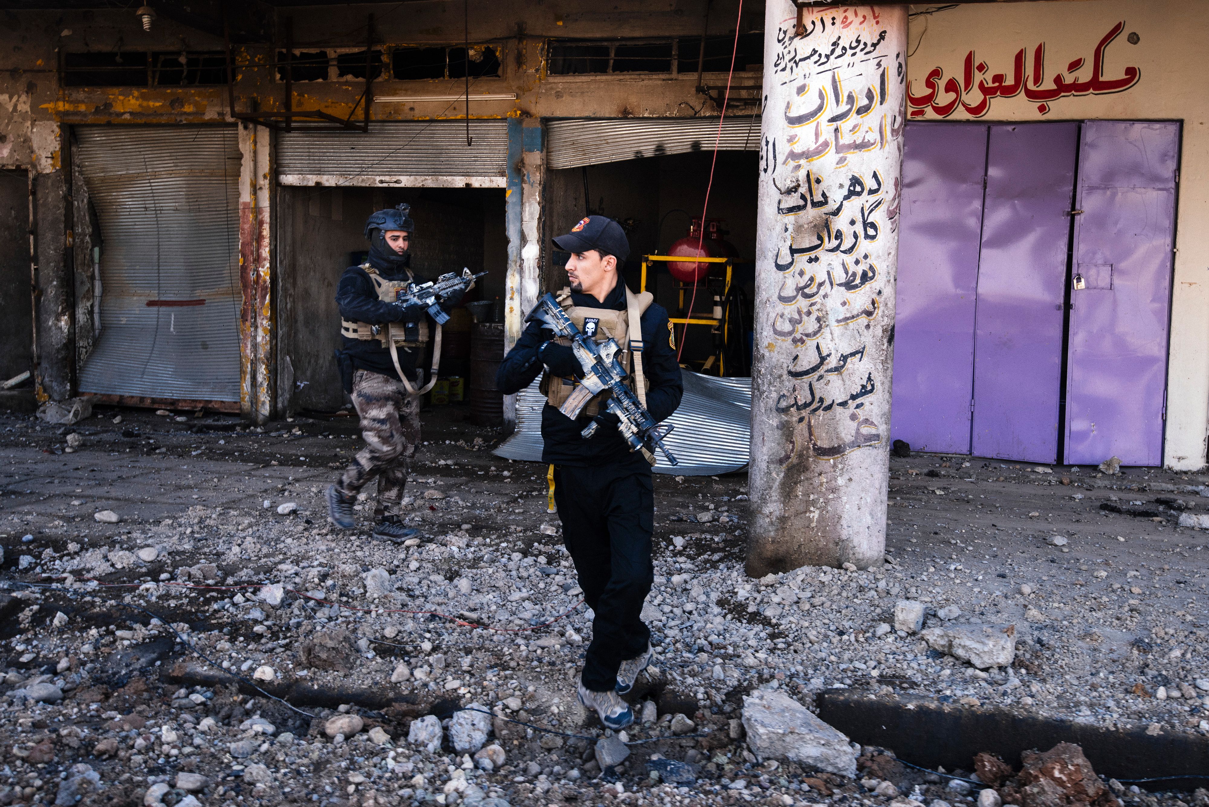 TOPSHOT - Members of the Iraqi special forces Counter Terrorism Service (CTS) walk next to destroyed shops in eastern Mosul on January 18, 2017. Iraqi forces have fully retaken east Mosul fro