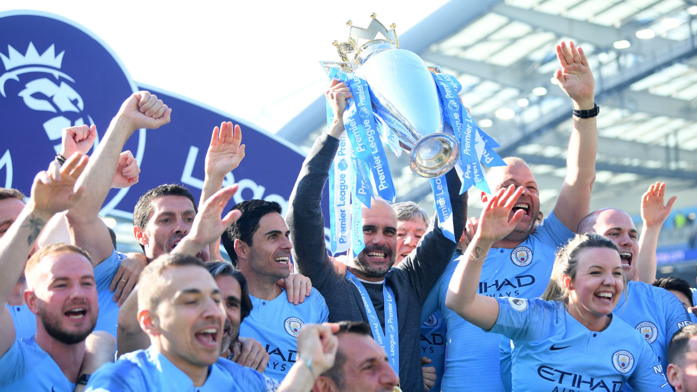 Man City manager Pep Guardiola lifts the Premier League trophy and celebrates with his staff