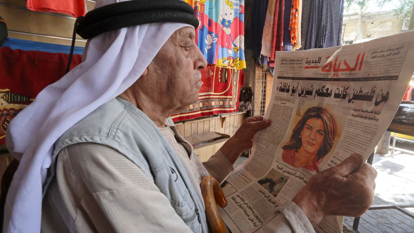 A Palestinian man reads the front page of a newspaper reporting on the death of veteran Al-Jazeera journalist Shireen Abu Akleh,