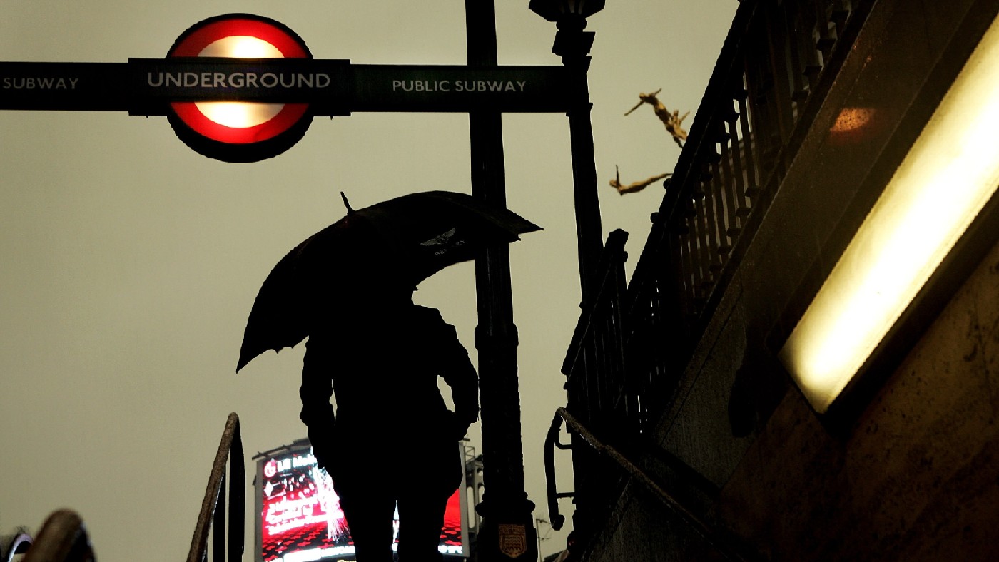 Man holds umbrella outside London Underground station 