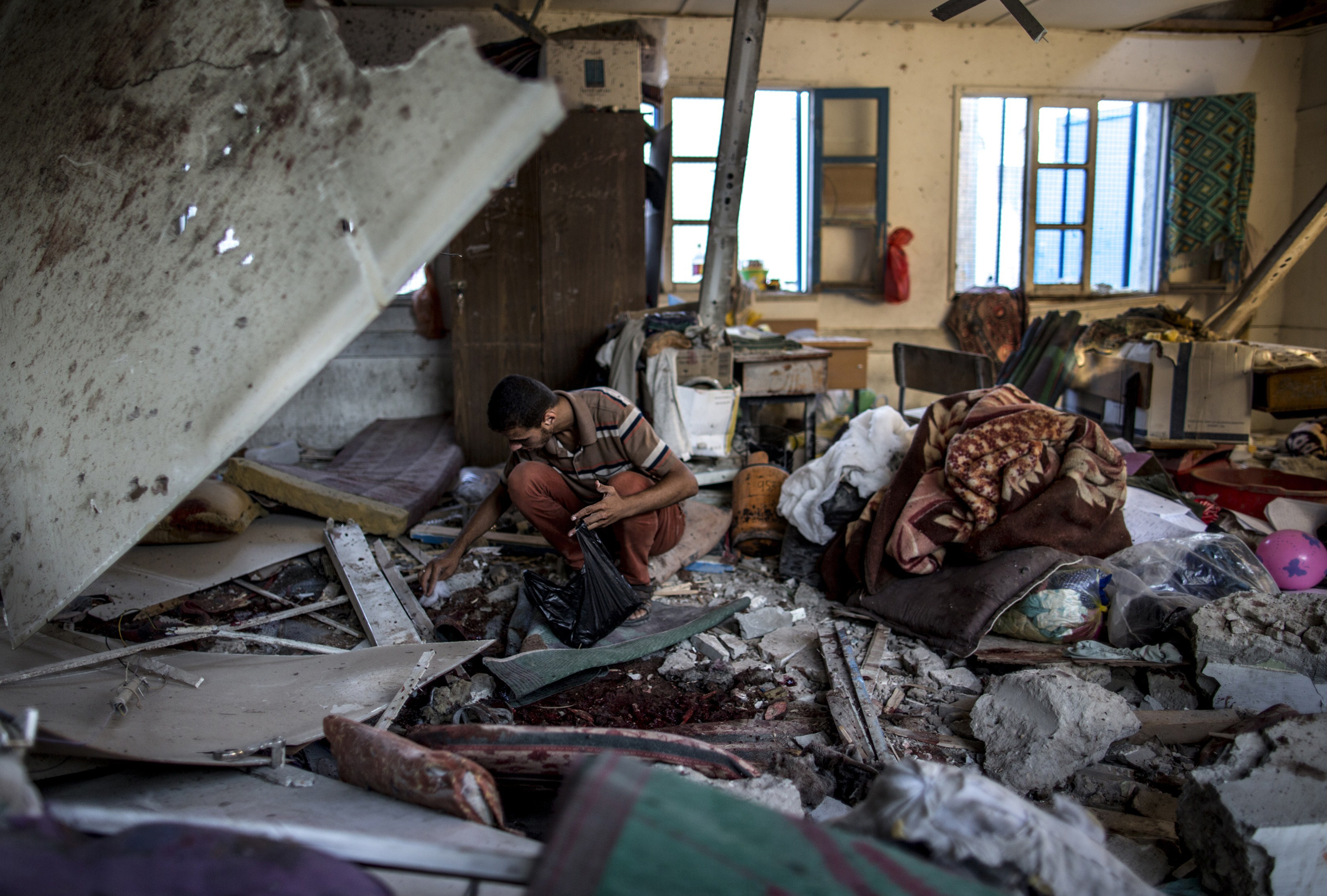 A Palestinian collects human remains from a Gaza school